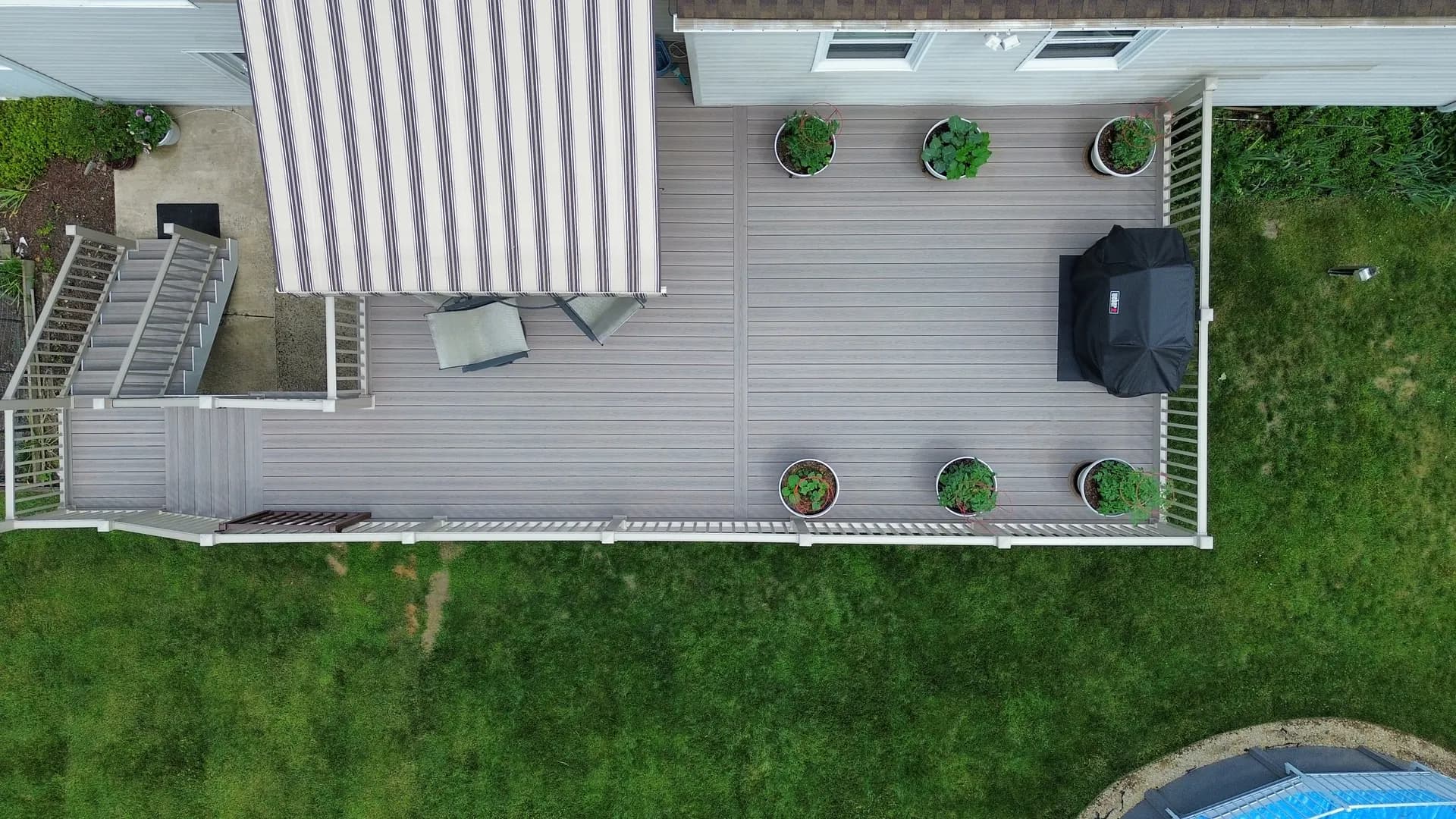 Top-down drone view of a custom composite deck in New Jersey showing clean board lines, planters and a grill area