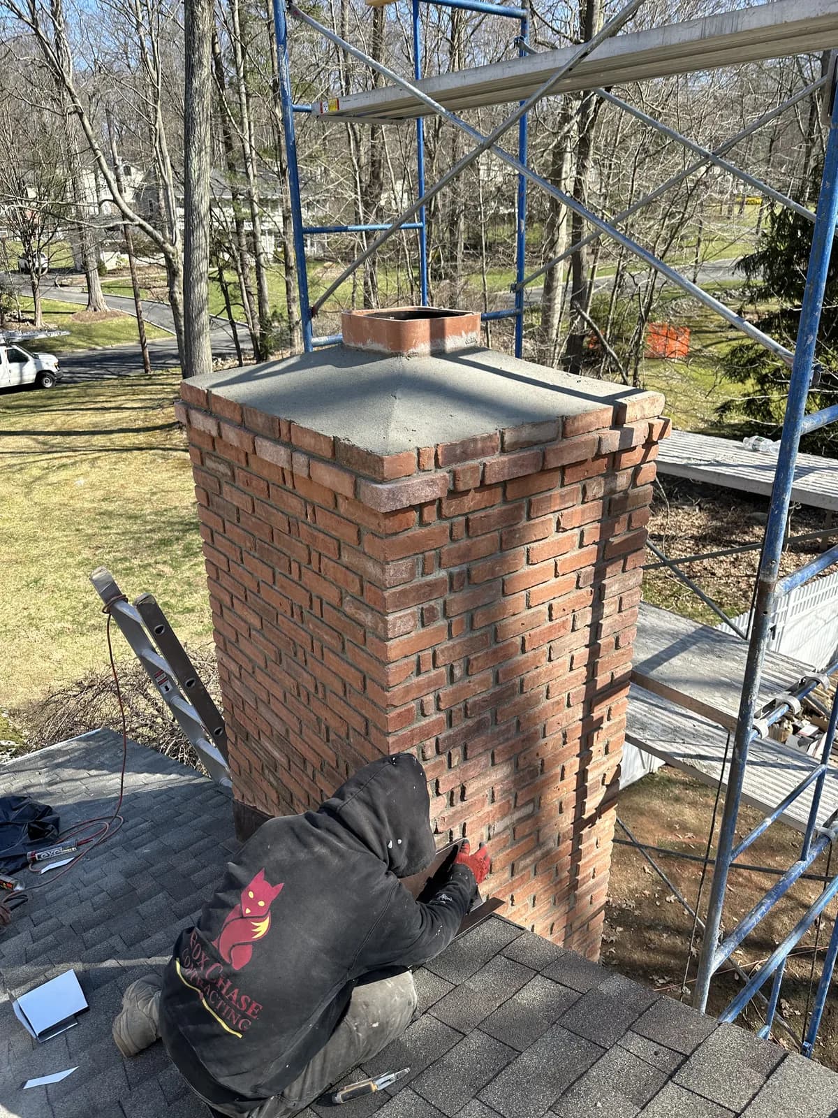 Father & Sons mason rebuilding a red-brick chimney with a fresh concrete crown in NJ