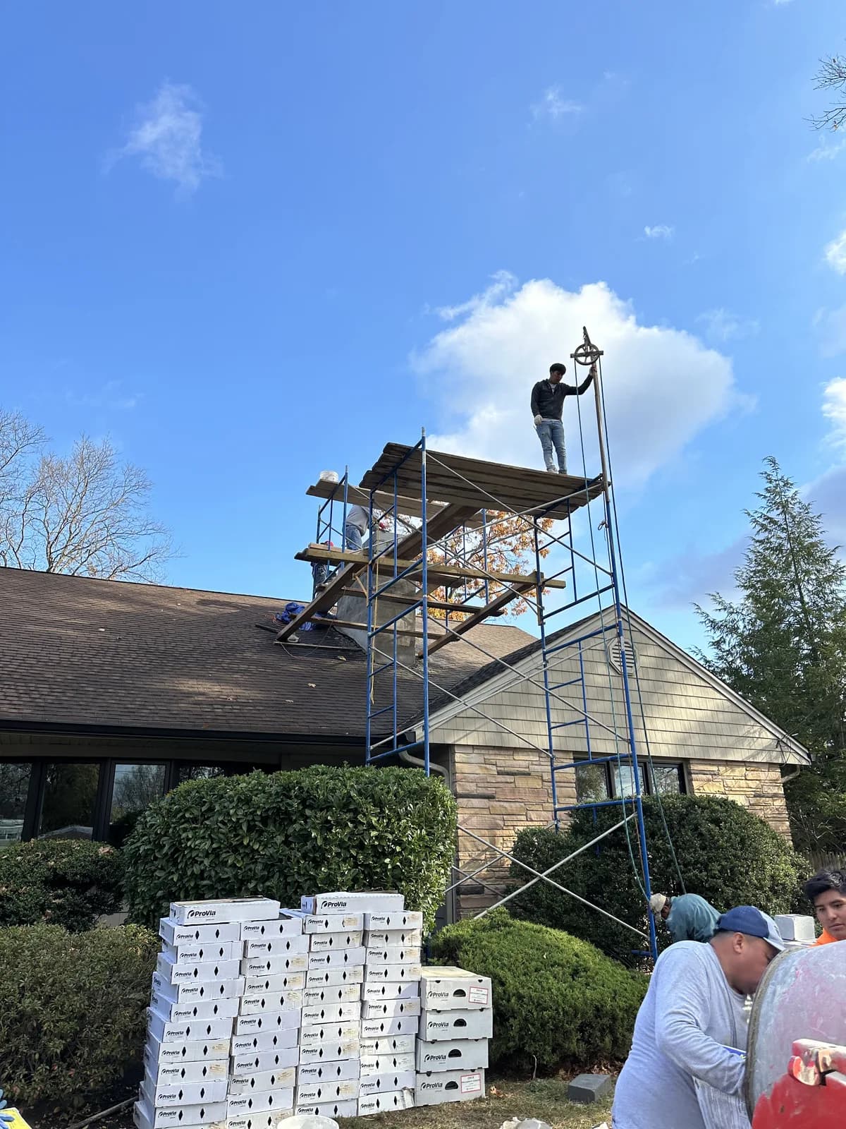 Masons repairing a chimney on a New Jersey roof using scaffold staging